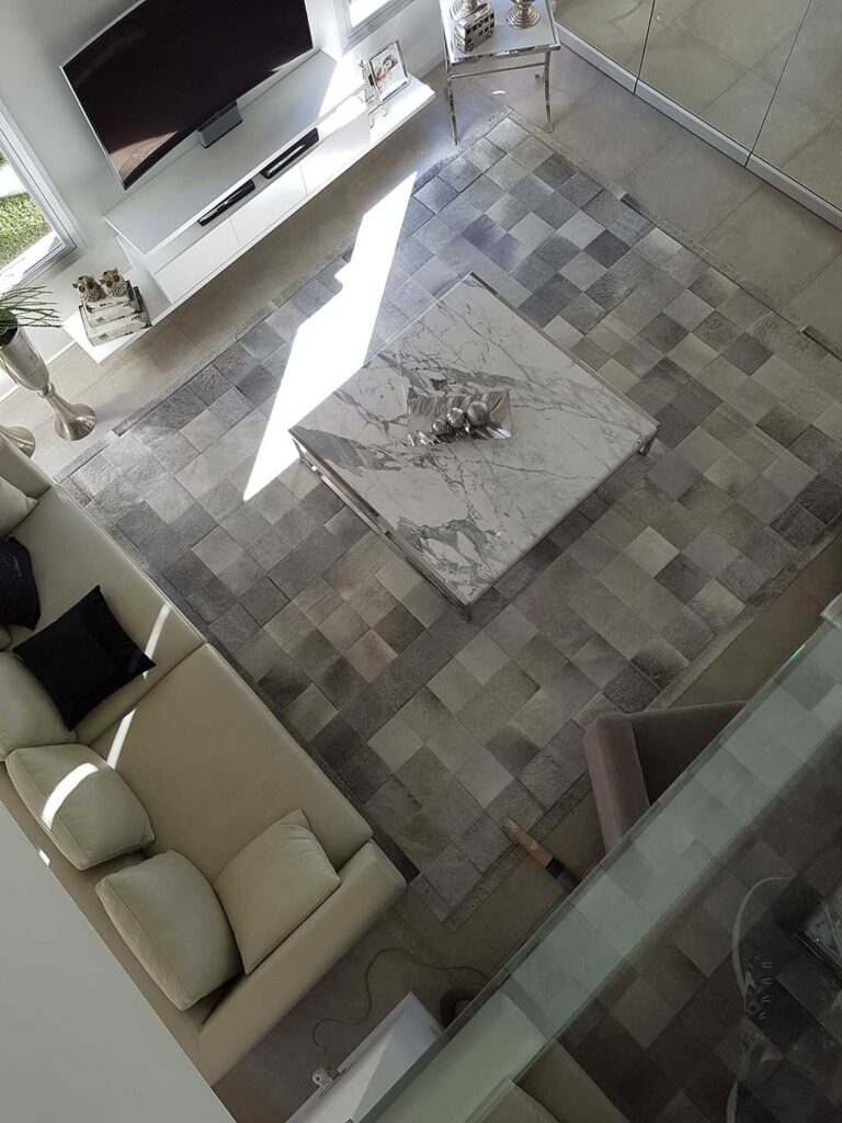 Top view of gray patchwork cowhide rug in a living room