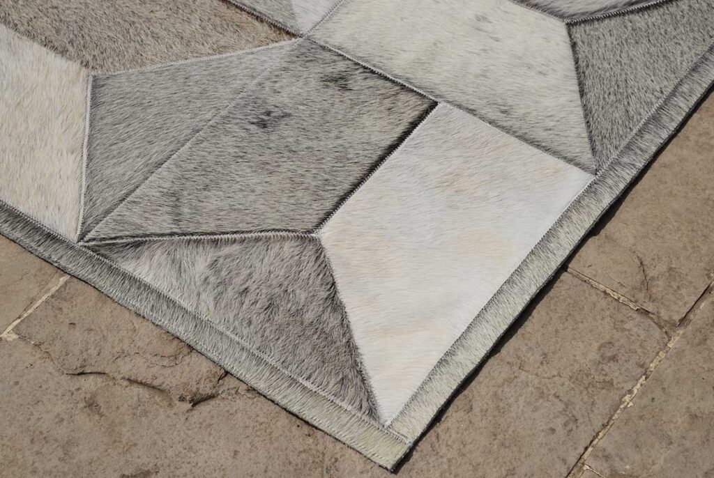 Detail of a taupe gray patchwork cowhide rug in our Envelope pattern