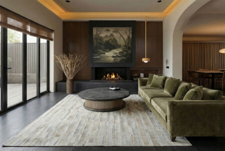 222-japandi-living-room-with-white-striped-patchwork-cowhide-rug Japandi style living room featuring an olive green sofa and a white striped patchwork cowhide rug, round black marble coffee table and soft lighting