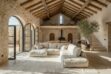 White squares patchwork cowhide rug in Mediterranean living room with stone walls and neutral sofa