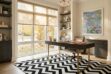 Black and white chevron patchwork cowhide rug in a chic, luxury home office with dark wood desk and autumn window view