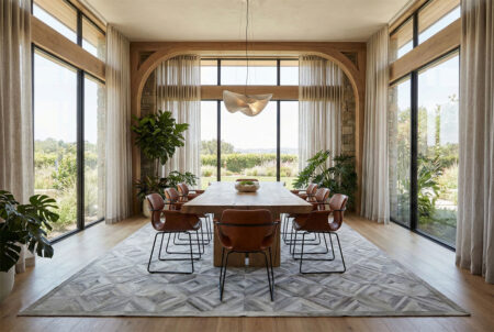 284-organic-architecture-dining-room-with-gray-diamond-patchwork-cowhide-rug Gray and white diamond patchwork cowhide rug in a modern dining room, styled under a heavy oak table with tobacco leather chairs and floor-to-ceiling windows.