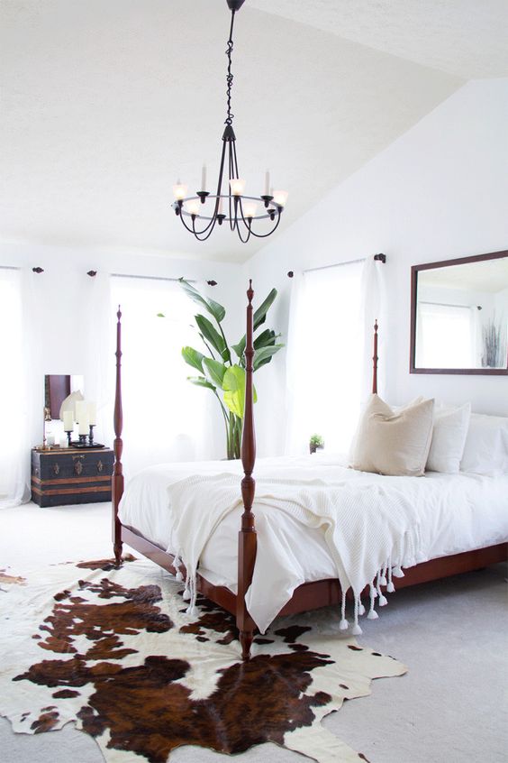 Cowhide rug in a bright bedroom with a four-post bed