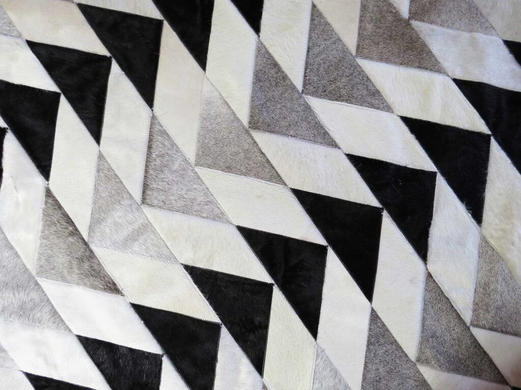 Custom patchwork cowhide rug in triangles and parallelograms in white, black and gray