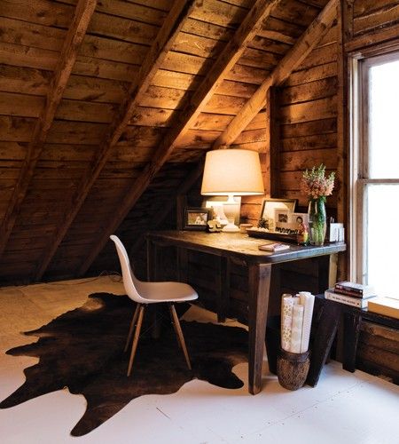 Brown cowhide rug with white floor and wooden ceiling in a winter cottage