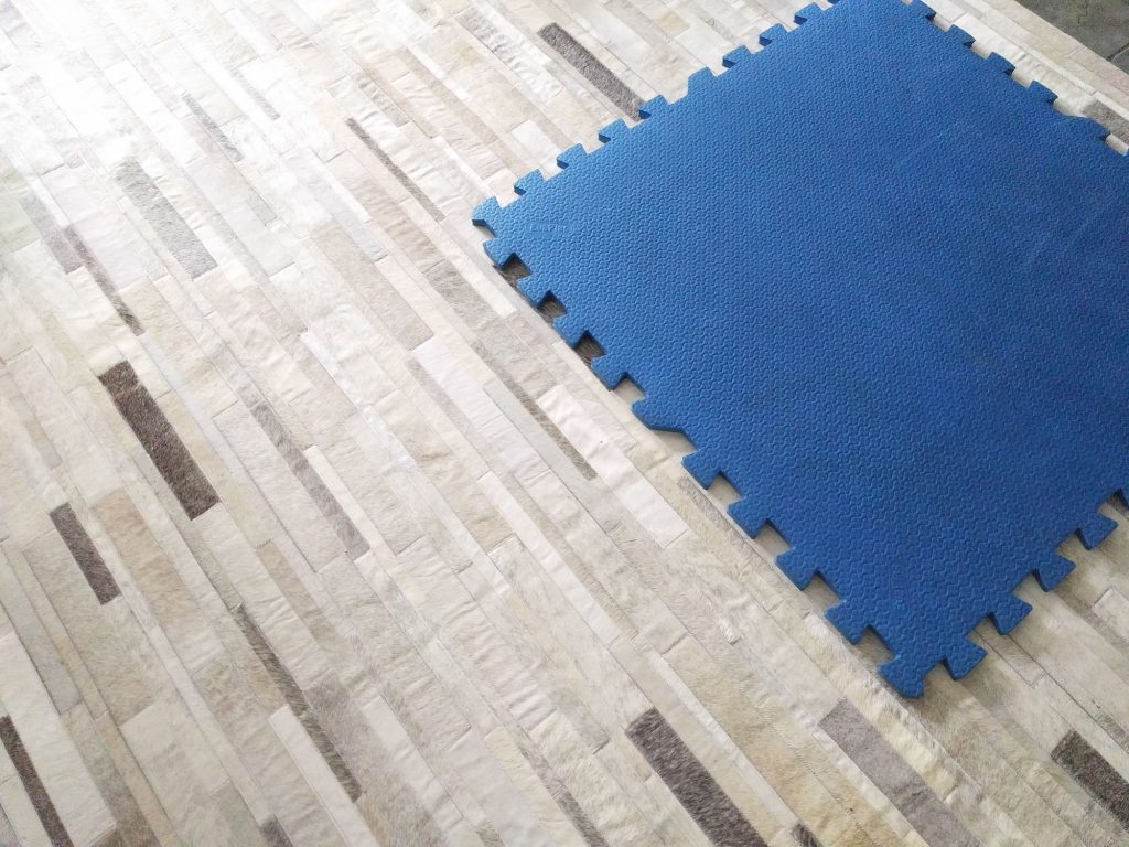 Rubber playing mat on a gray and white patchwork cowhide rug