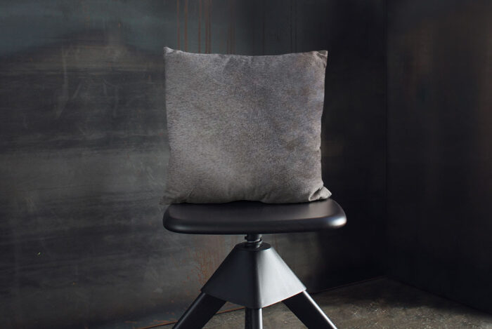 Unique Taupe Gray Cowhide Throw Pillow on Wooden Stool