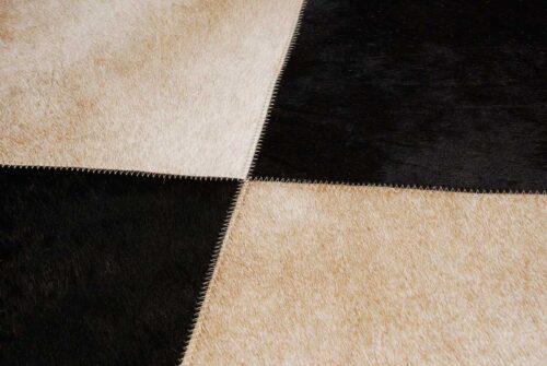 Hair detail of a beige and black cowhide patchwork rug in Squares