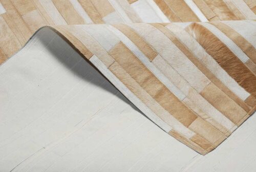 Beige and white patchwork cowhide rug designed in stripes with backing