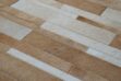 Hair on hide detail of Beige and white patchwork cowhide rug designed in stripes