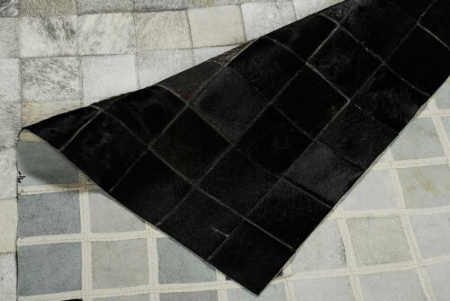 White, gray and black patchwork cowhide rug in squares showing the backing