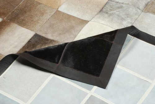 Detail of a Square tiles brown, beige and black cowhide patchwork rug