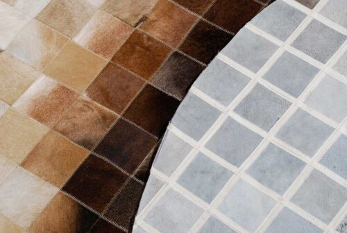 Close up of a Round Beige and Brown gradient patchwork cowhide rug with backing