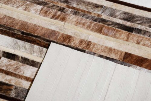 Detail of a brindle, brown and white patchwork cowhide rug in a striped design with the backing