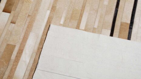 Detail of a Beige and chocolate Patchwork Cowhide Rug Designed in stripes with backing