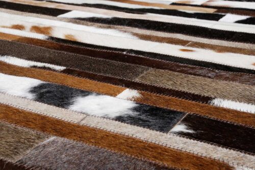 Hair on hide detail of white, brown and black patchwork cowhide rug designed in stripes