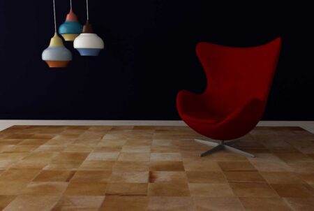 Beige Cowhide Patchwork Rug in Squares with a modern chair and lights Beige Cowhide Patchwork Rug in Squares with a modern chair and lights