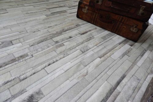 Detail of a gray and white patchwork cowhide rug in stripes