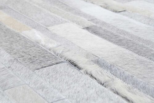Hair on hide detail of gray and white patchwork cowhide rug in stripes