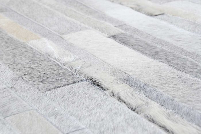 Hair on hide detail of gray and white patchwork cowhide rug in stripes