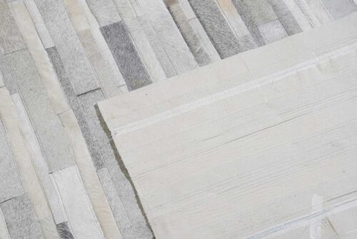 Backing of a hair on hide detail of gray and white patchwork cowhide rug in stripes