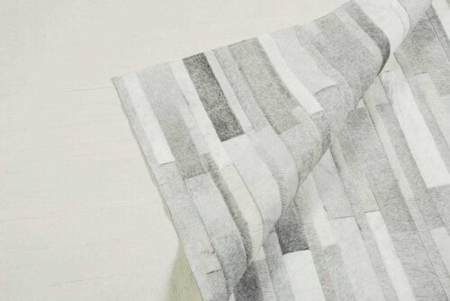 Backing of a hair on hide detail of gray and white patchwork cowhide rug in stripes