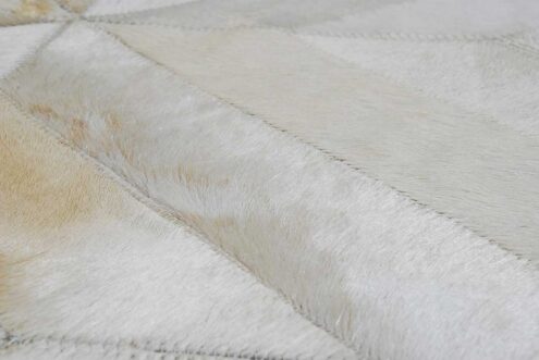 Hair on hide detail of beige patchwork cowhide rug in diamond design Hair on hide detail of beige patchwork cowhide rug in diamond design