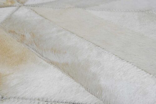 Hair on hide detail of beige patchwork cowhide rug in diamond design