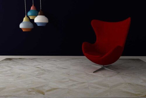 Beige patchwork cowhide rug in chevron design with modern chair on