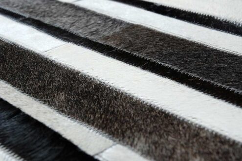 Hair on hide detail of white, gray and black cowhide patchwork rug in stripes Hair on hide detail of white, gray and black cowhide patchwork rug in stripes