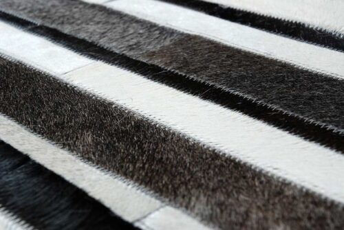 Hair on hide detail of white, gray and black cowhide patchwork rug in stripes