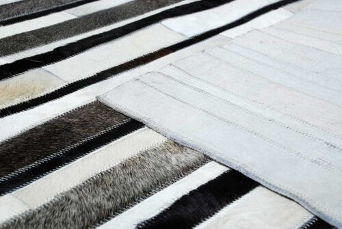 White, gray and black leather area rug in stripes with backing