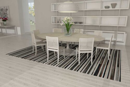 White, gray and black cow hide patchwork rug in dining room