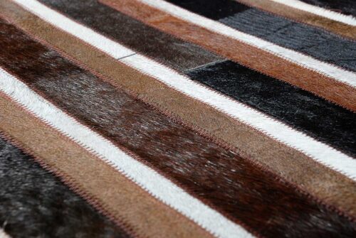 Hair on hide detail of black, brown and white patchwork cowhide rug in stripes