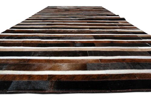 Floor view of black, brown and white patchwork cowhide rug in stripes