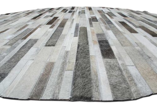 View of a round gray cowhide patchwork rug designed in stripes