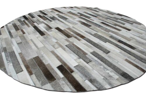 General view of a round taupe gray cowhide patchwork rug in stripes