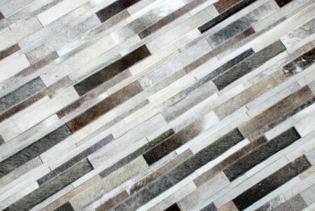 Top view of a taupe gray cowhide patchwork rug designed in Stripes Top view of a taupe gray cowhide patchwork rug designed in Stripes