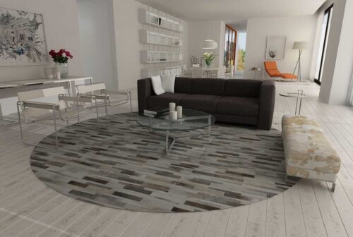 Round taupe gray cowhide patchwork rug designed in stripes in a white modern living room