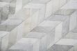 Detail of a light gray cowhide patchwork rug in chevron design