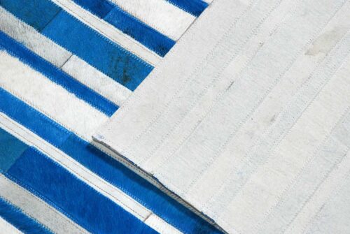 Detail of Blue and white cowhide patchwork rug in stripes design with backing