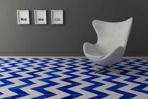 Blue and white cowhide patchwork rug in a chevron design with a modern chair on