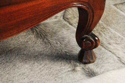 Hair on hide detail of our gray Cube patchwork cowhide rug with antique furniture legs