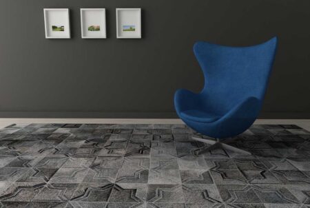 Dark gray patchwork cowhide rug in a moorish star design with a modern blue chair and dark walls Dark gray patchwork cowhide rug in a moorish star design with a modern blue chair and dark walls
