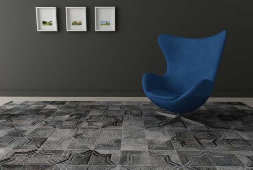 Dark gray patchwork cowhide rug in a moorish star design with a modern blue chair and dark walls