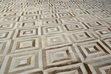 Primer plano de alfombra patchwork de cuero de vaca blanco y beige con diseño de rombos Primer plano de alfombra patchwork de cuero de vaca blanco y beige con diseño de rombos