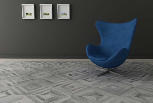 Diamond gray cowhide patchwork rug with a blue modern chair on