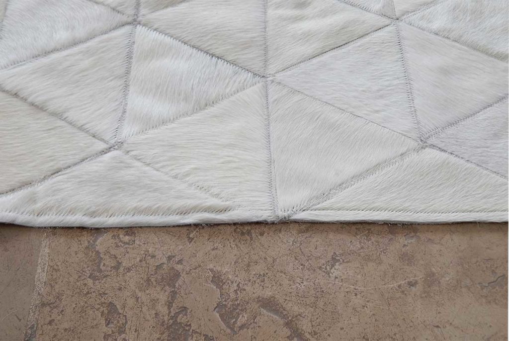 Detail of white patchwork cowhide rug on dark floor