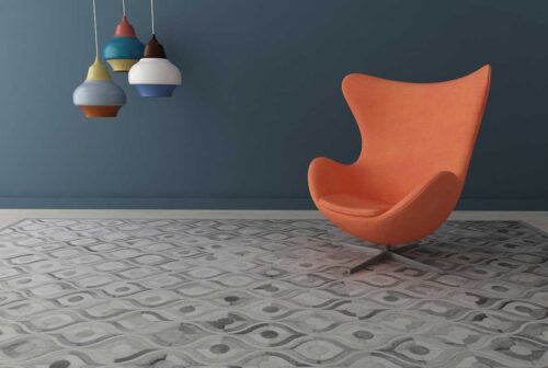 Gray Patchwork Cowhide Rug in our River Design with a coral Egg chair and dark blue wall