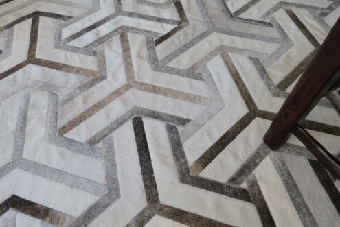 White, taupe and gray cowhide patchwork rug Wooden chair White, taupe and gray cowhide patchwork rug Wooden chair